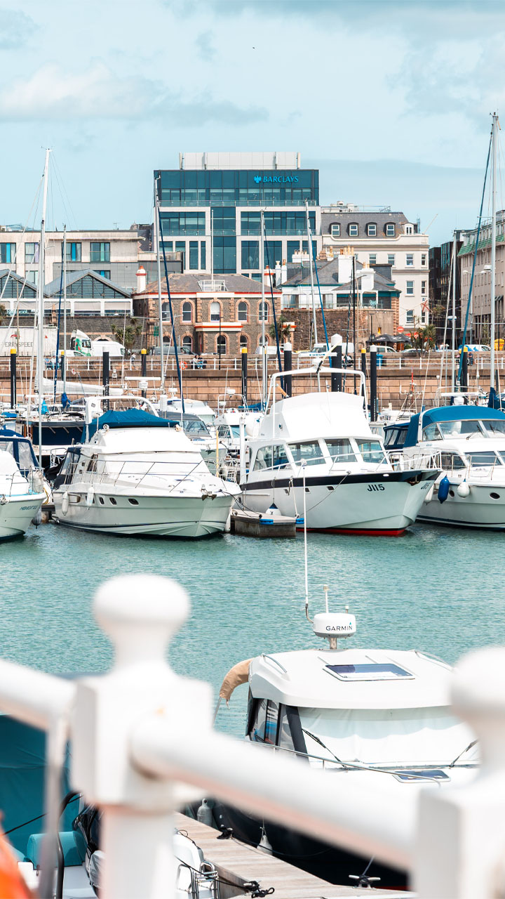 Sunny marina and yachts floating at mid-tide.